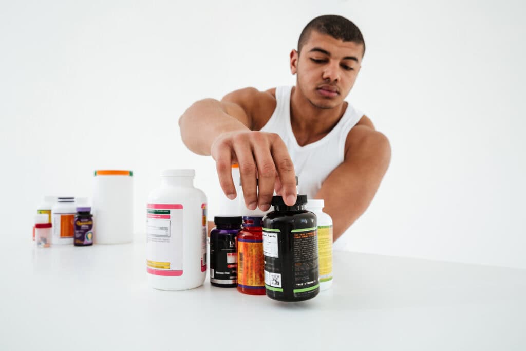 Sportman staat op een witte achtergrond en houdt vitamines vast