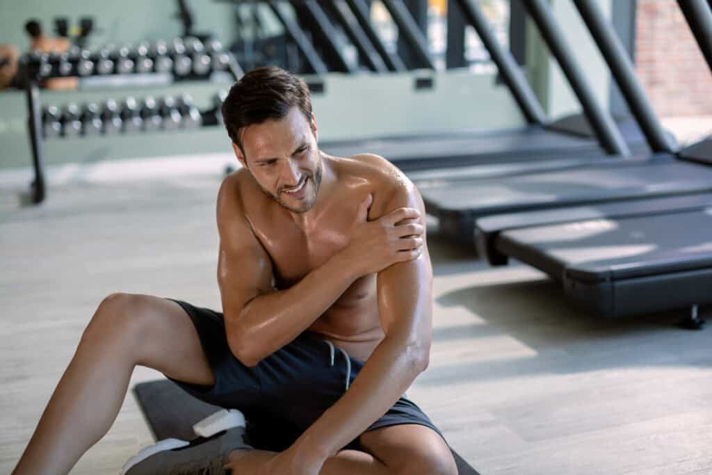 Jonge atleet houdt zijn schouder vast na een sporttraining
