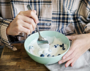 Kaukasisch meisje eet yoghurt op bed